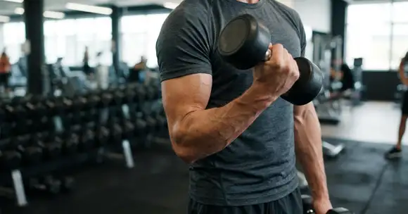 Entrenador realizando ejercicio de bíceps con mancuerna, enfocado en el acondicionamiento físico y cómo responde el cuerpo al movimiento.